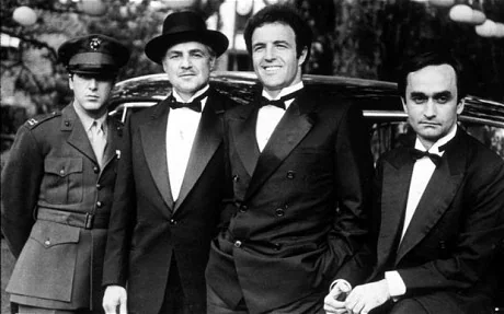 Four characters from the Godfather movie standing in front of a car